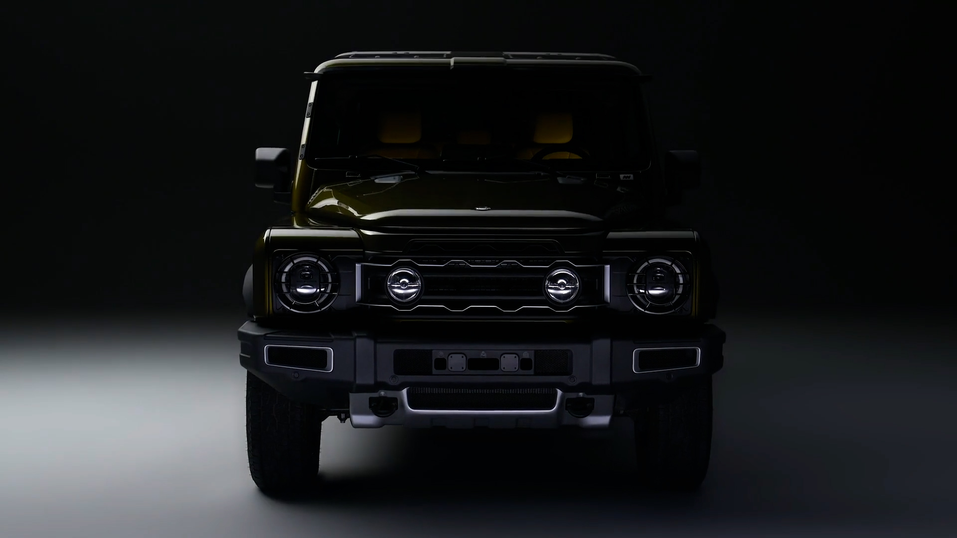 Photograph of a black SUV captured from the front against a dark background with subtle lighting highlighting its grille, headlights, and bumper. The vehicle's rugged design and circular headlights are prominent, emphasizing its robust and modern appearance.